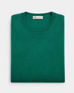 Maglia girocollo in lana merinos verde Affinito, piegata su fondo bianco